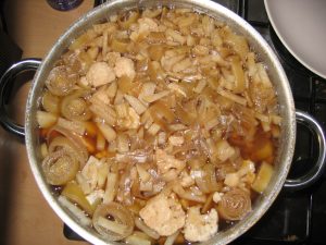 A tan and beige colored stew featuring onions and cauliflower still simmering on the stovetop.