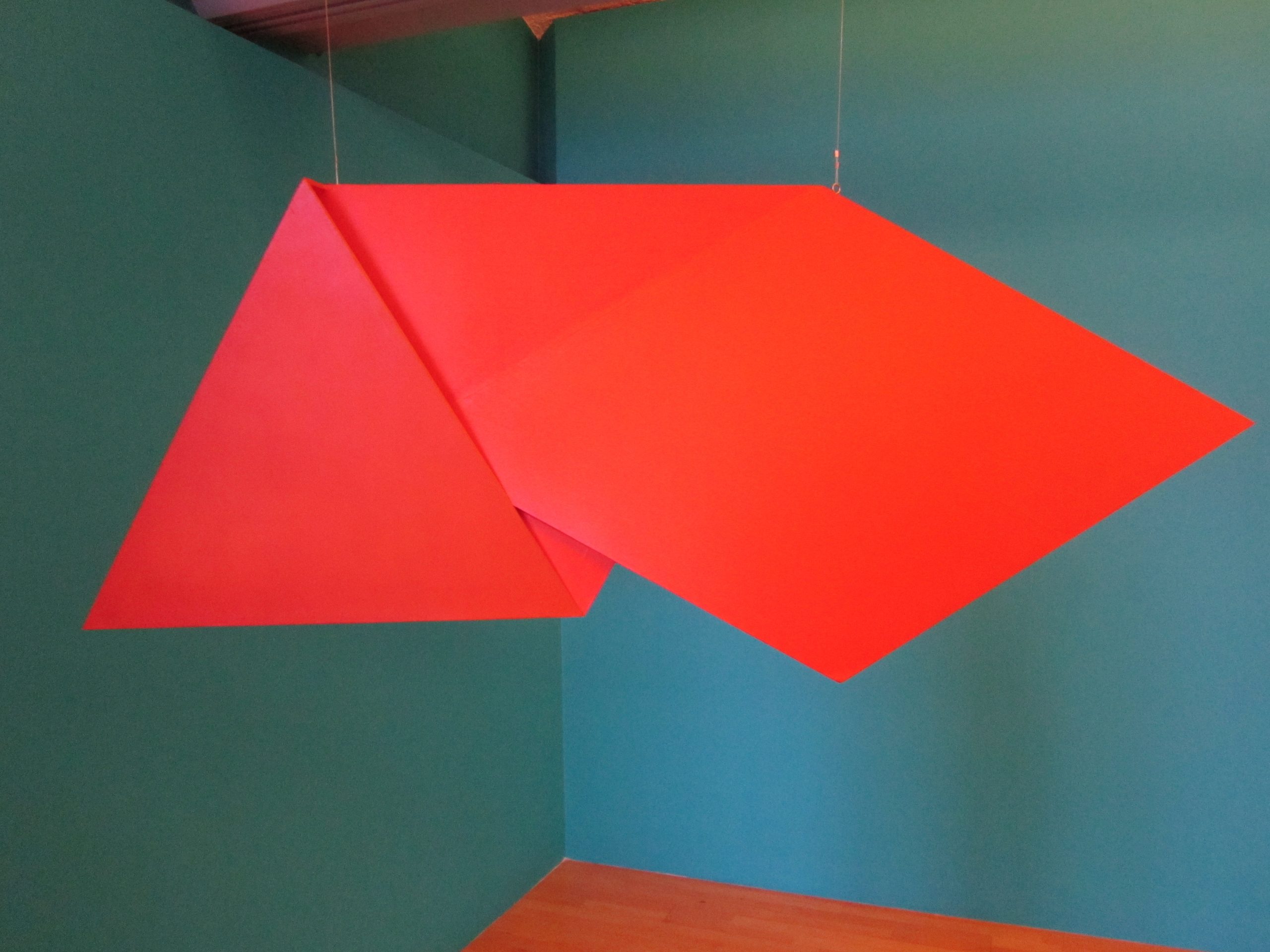 A red panel hanging from the ceiling, with the edges folded in on itself in a few different angles.